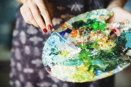 油画班女人的手拿着画笔和油画颜料的调色板.闭合.艺术观念照片