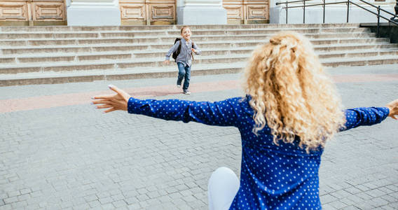 幸福的母子俩奔跑着,拥抱着,旋转着在校外的教学楼前见面.照片