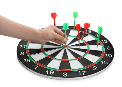 准确的射击游戏年轻女子在白色背景下把飞镖从板上拿出来,特写照片