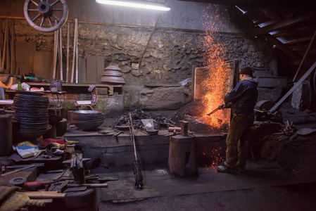 年轻的传统铁匠在明火中工作图片