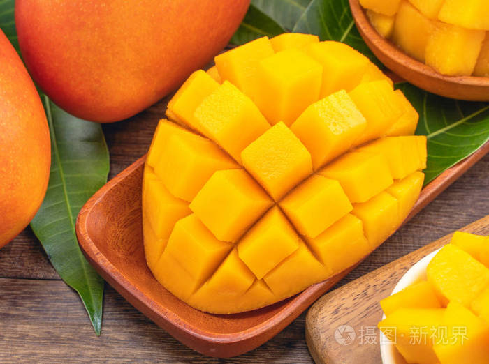 新鲜切碎的芒果块放在木制切碎板上背景为乡村木材热带夏季水果概念