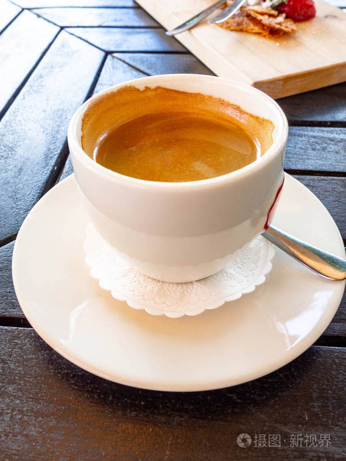 美味的白色卡布奇诺咖啡杯和拿铁艺术在木桌上