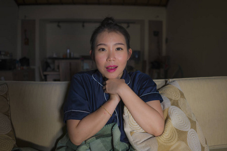 在家客厅舒适地坐在沙发沙发上看电视剧或浪漫喜剧电影微笑甜蜜女人拿