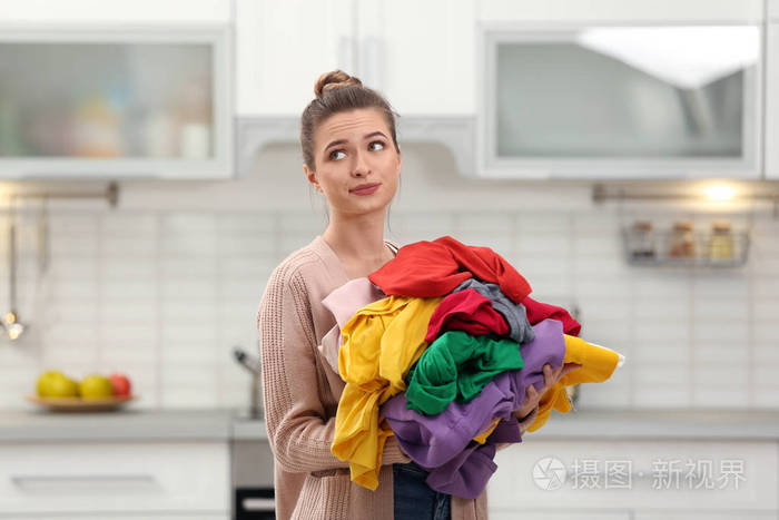 厨房里拿着一堆脏衣服的女人