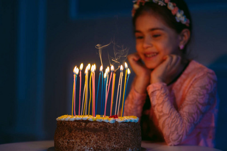 一个可爱的小女孩在炉灶上吹灭蜡烛照片