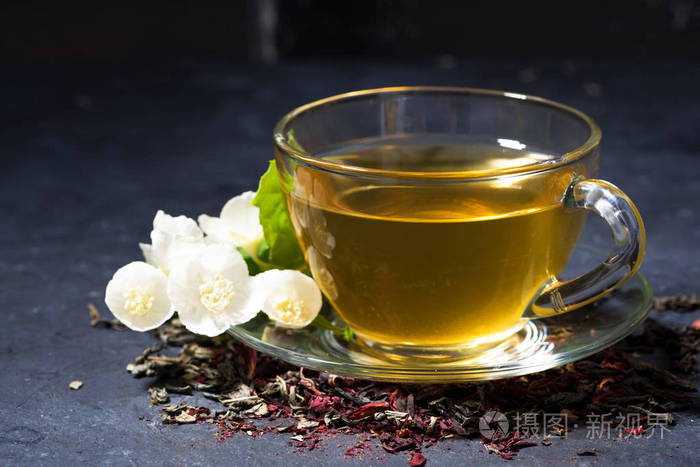 一杯芳香的茉莉花茶放在一张深色的桌子上
