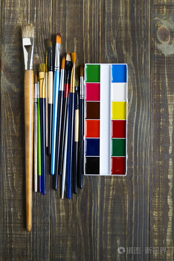 一种水彩画调色板和画笔,用于在有复印空间的深色木制桌子上作画.