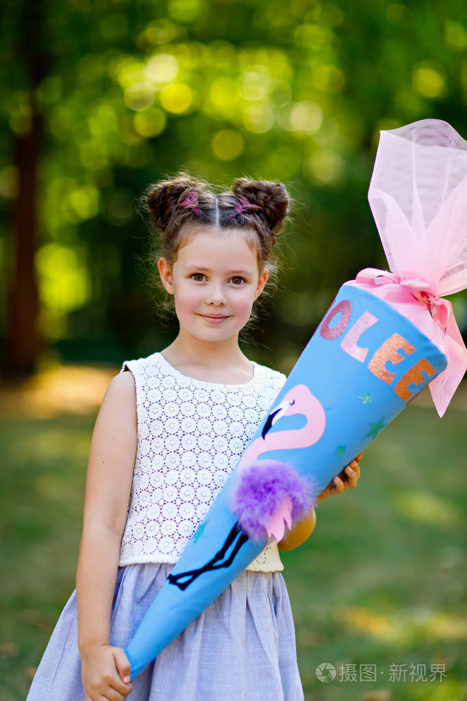 快乐的小女孩带着背包或书包和德国传统的大书包或圆锥体上学的第一天