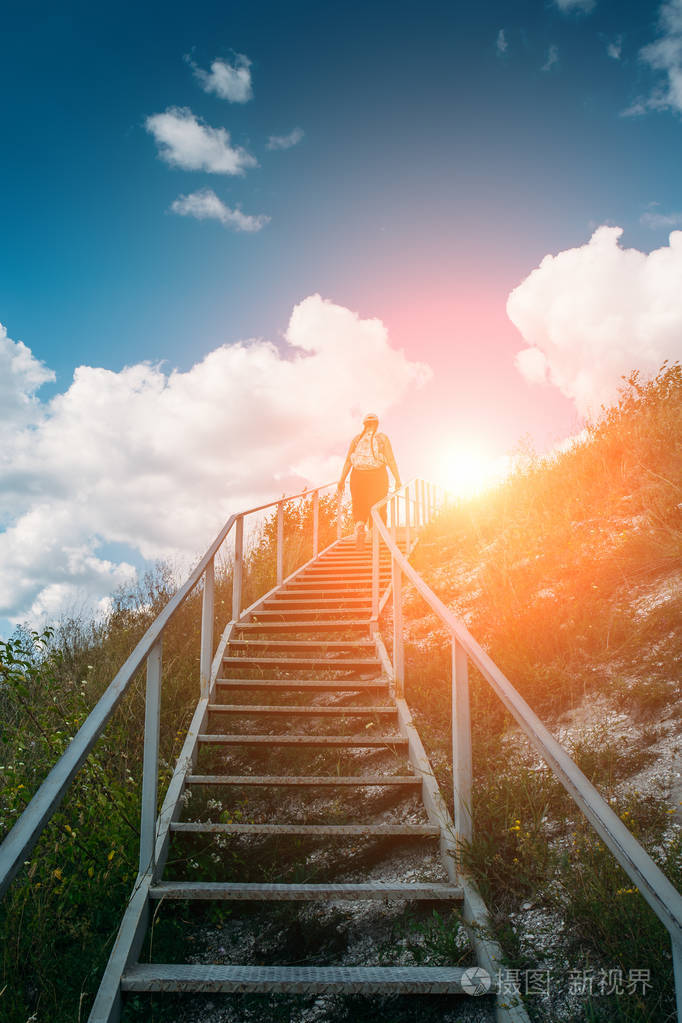 年轻女孩游客攀登或登上高山上的大型钢楼梯夏季旅行冒险概念