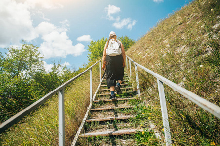年轻女孩游客攀登或登上高山上的大型钢楼梯,夏季旅行冒险概念照片