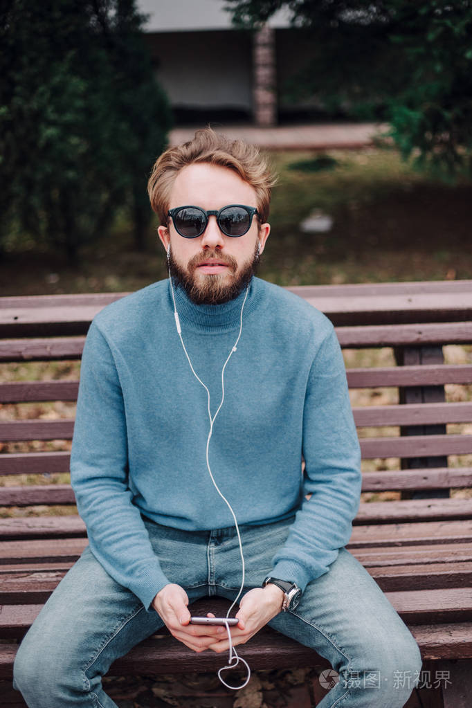 年轻的时髦男同性恋听音乐耳机