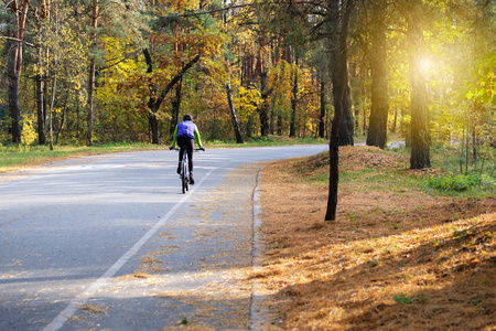 在阳光明媚的日子里骑着自行车在许多树中间.健康的生活方式.