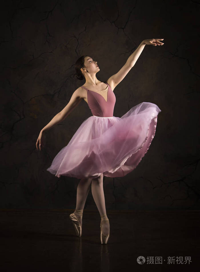 穿着粉红色裙子和米色上衣的苗条女孩跳芭蕾舞