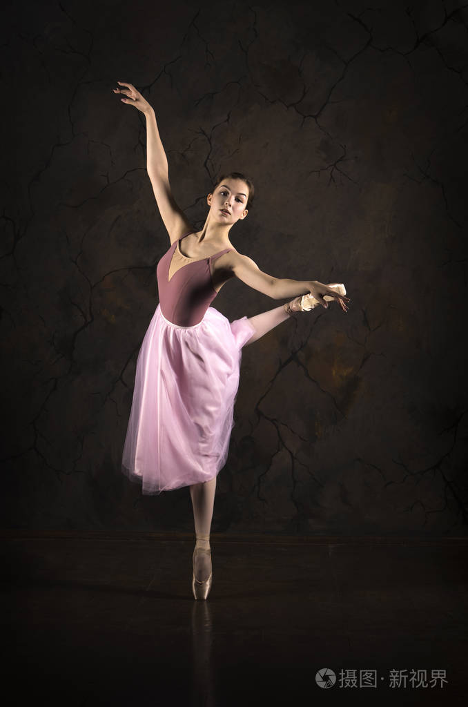 穿着粉红色裙子和米色上衣的苗条女孩跳芭蕾舞