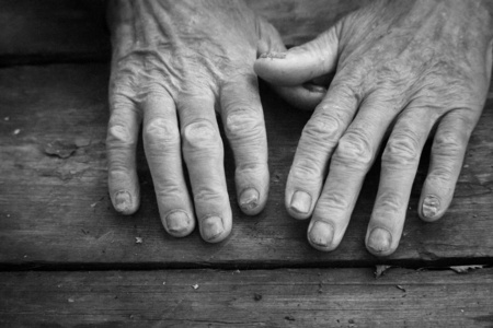 老弱黑白照片,老弱病弱的男性手放在古董粗糙的木质表面上,诉说和求助