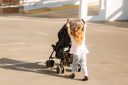 一个小女孩推着她的婴儿车.儿童推车后视图照片