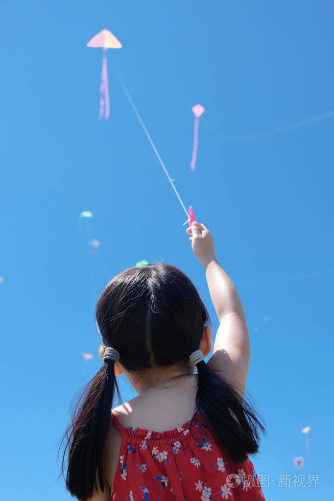 在阳光明媚的夏日里放风筝的小女孩