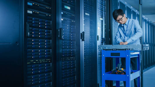 在现代数据中心:it技术人员正在处理服务器机架,在安装新硬件的推车上