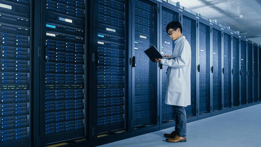 站在服务器机架旁,用笔记本电脑运行维护诊断工具,进行控制,使数据库