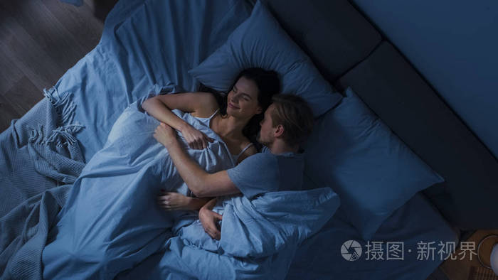 可爱的年轻夫妇甜蜜地睡在床上男人们在梦中温柔地拥抱着她微笑的女友