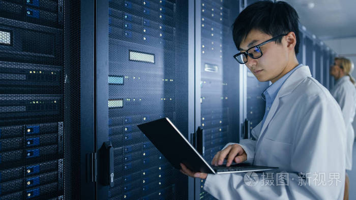 在数据中心穿着白大褂的男女it专家在服务器机架上工