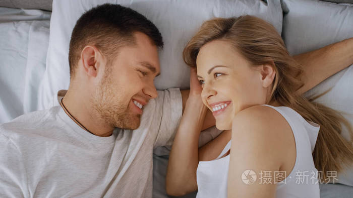 幸福的小夫妻依偎在床上年轻的女人怀孕了爱人温柔地抚摸着她俯视图