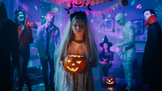 鬼新娘万圣节服装派对:穿着的白色新娘礼服的小女孩抱着吓人的洋娃娃.