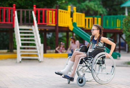操场前,一个腿断了的女孩坐在轮椅上.照片