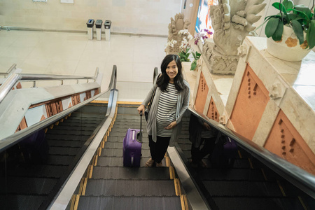亚洲孕妇站着拉行李箱图片