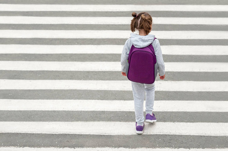 女学生在上学的路上过马路.斑马线在城市里步行.行人经过人行横道.