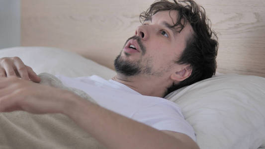 噩梦惊醒偶然的年轻人在床上被可怕的梦,噩梦惊醒照片