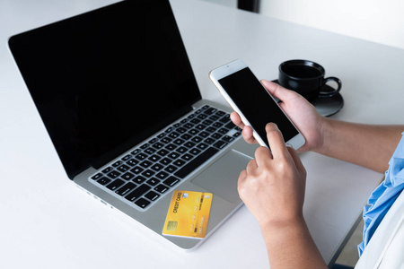 女人用信用卡在她的笔记本电脑和手机上进行网上购物照片
