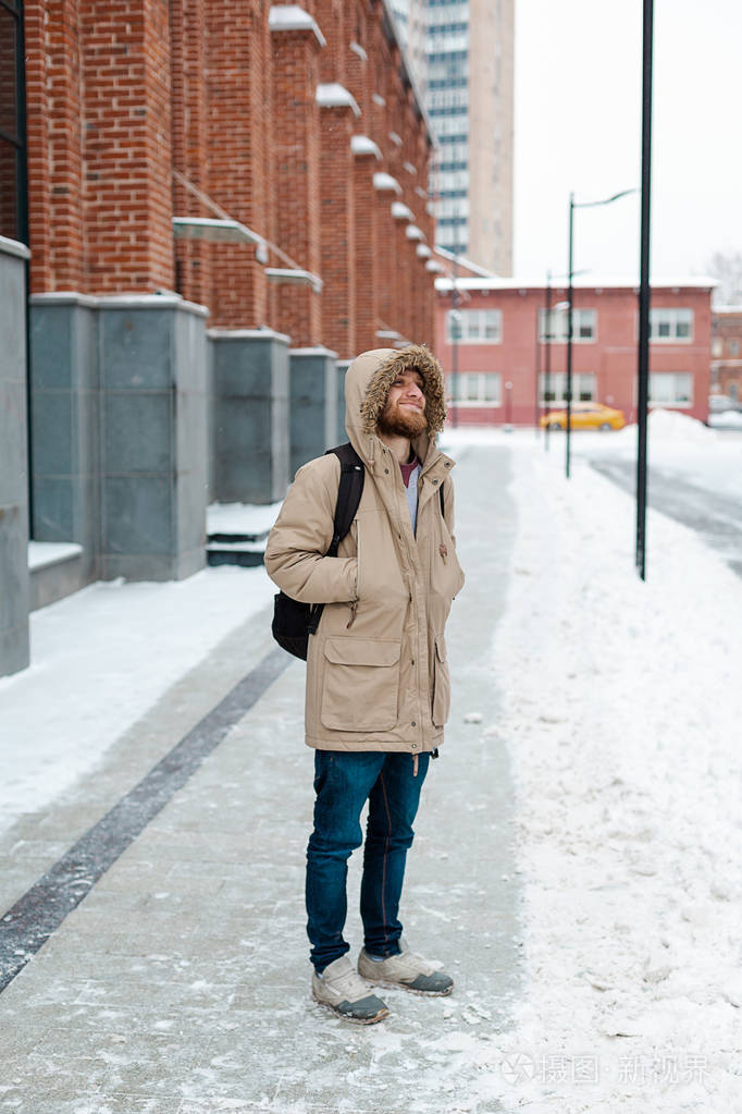 一个留着胡子的年轻人走在冬天的大街上