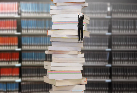 一摞高高的书,上面挂着一位正在攀爬的商人照片