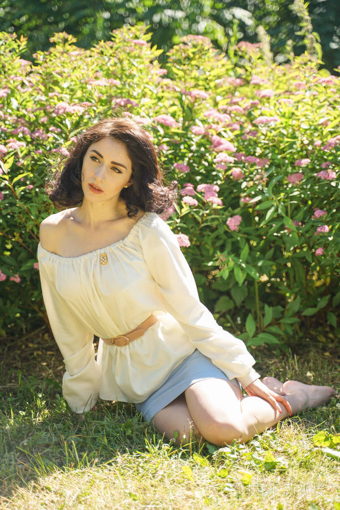 在城市公园享受阳光的成熟女人的特写镜头美丽的女士在绿草和绿树旁