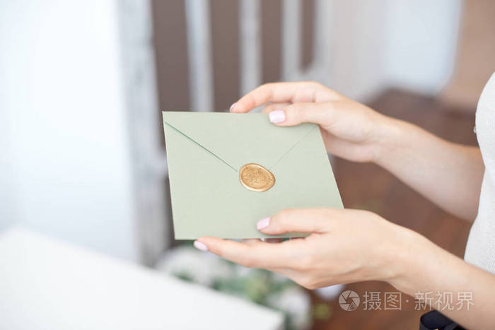 女性手拿蜡封请柬信封礼券明信片婚礼请柬的特写照片