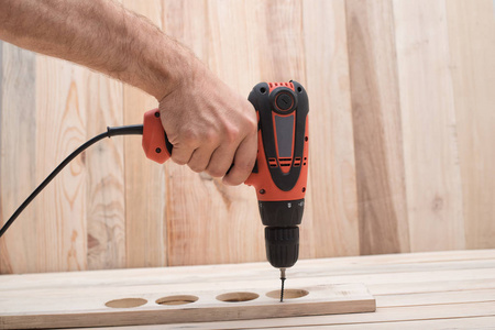 公刀公手电钻螺丝刀.拧紧螺丝,在浅棕色木桌上加工工件.照片