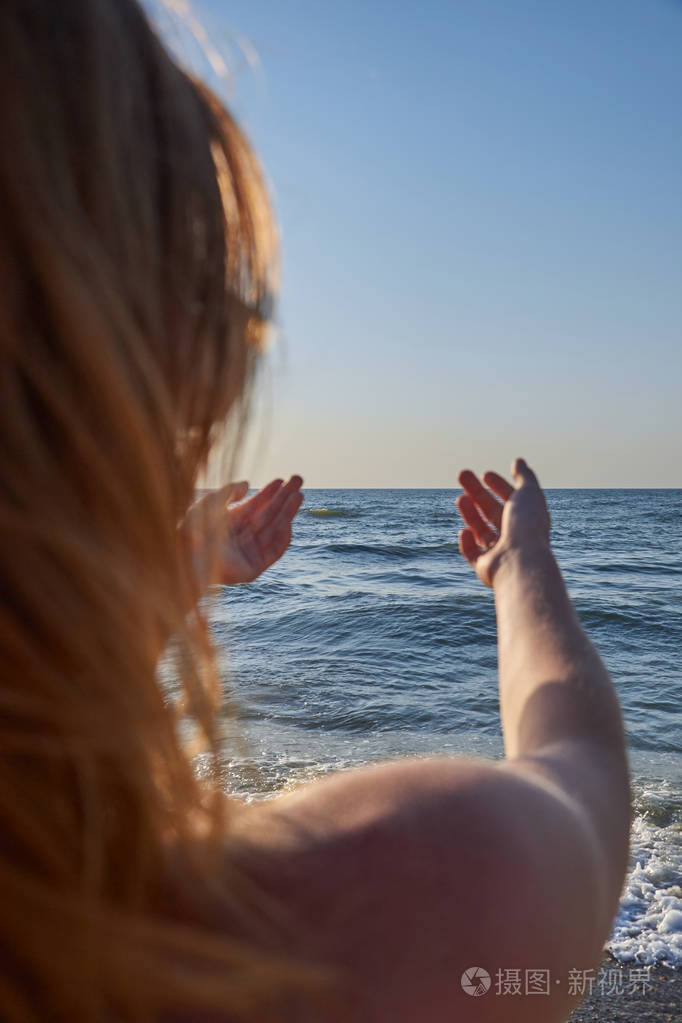 从背后望着大海的女人光着身子披着卷发女孩把手拉向大海