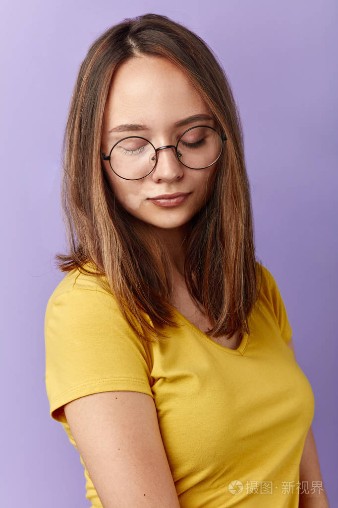 戴圆眼镜的害羞女孩低头看