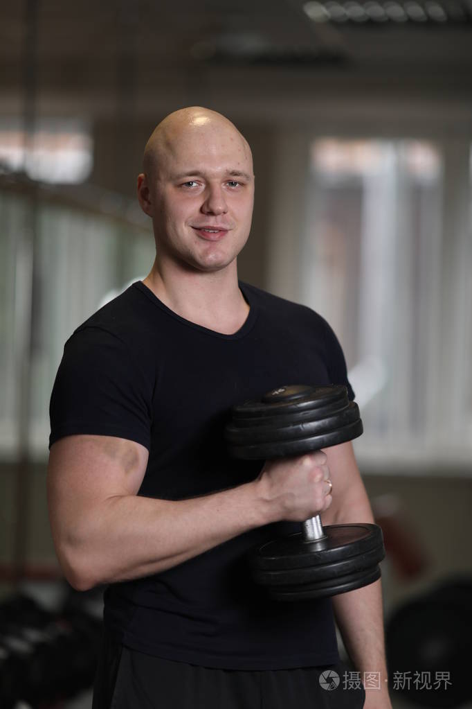 欧洲高加索男子健美运动员身穿黑色运动服手持哑铃手臂肌肉发达做二头