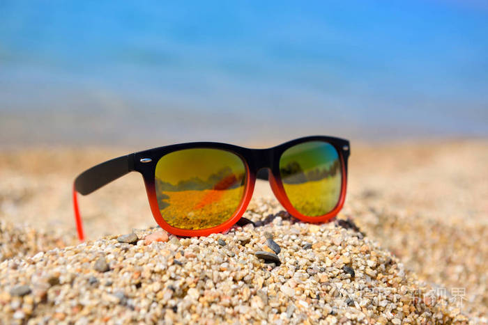 在阳光明媚的大白天在海边的海滩上戴着墨镜