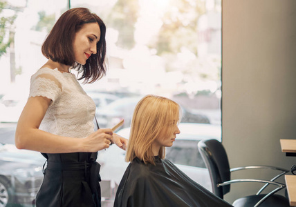 向上剪头woman hairdresser cuts hair of a beautiful blonde 照片