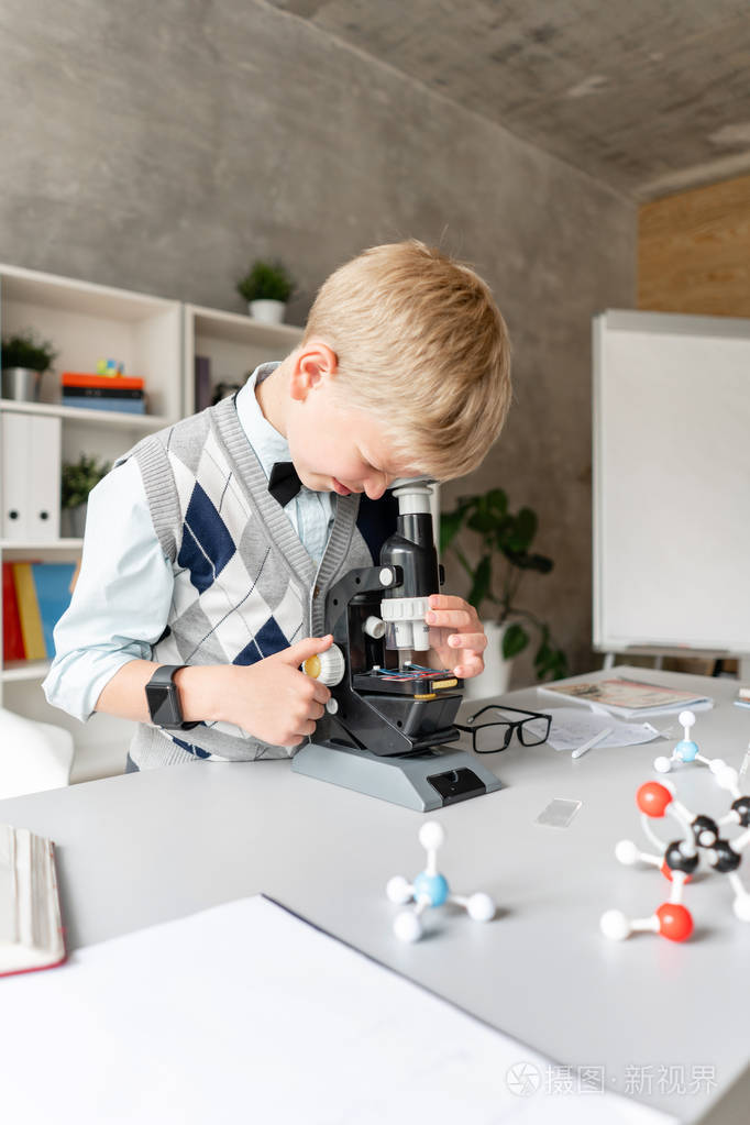 穿着便服的小男孩在显微镜下看