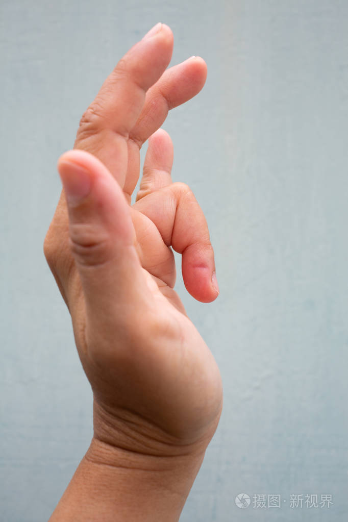 女性左手无名指扣扳机疼痛难忍蓝灰色背景特写和宏观拍摄办公室综合症
