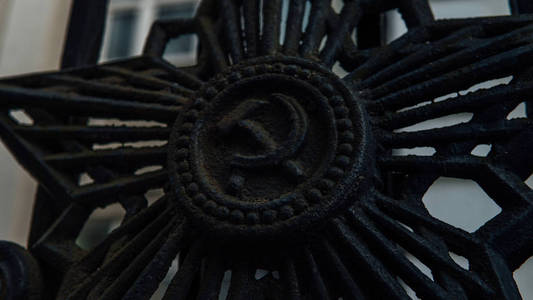 旧镰刀旧篱笆上的锤子和镰刀,苏联的象征.概念:不存在状态的纹章照片