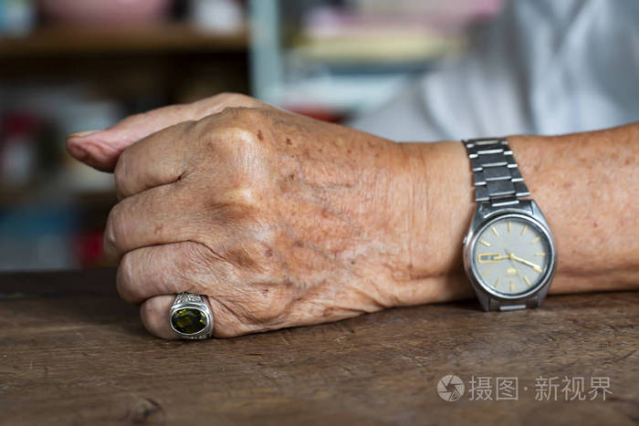 老人左手握拳在木桌背景上,痣和瑕疵,特写和宏拍,选择性聚焦,亚洲身体