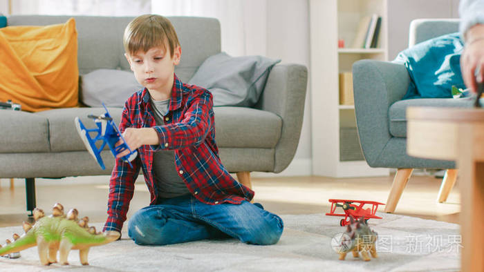 在家聪明的小男孩玩玩具飞机在阳光明媚的客厅里小孩子在地毯上玩耍