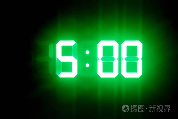 绿色发光的数字钟在黑暗中显示5点