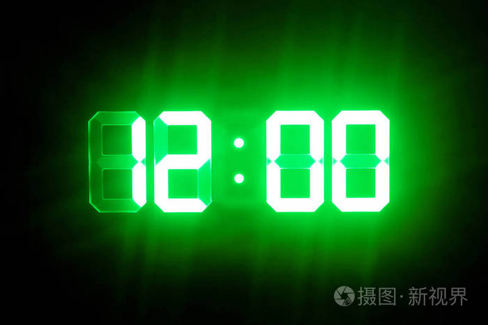 绿色发光的数字钟在黑暗中显示12点