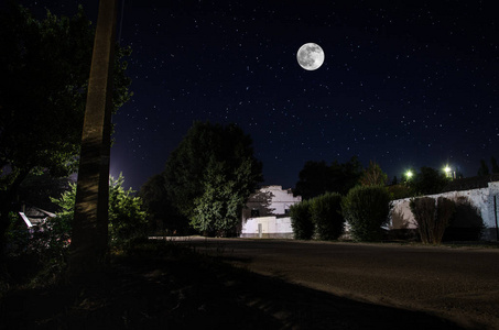 恐怖村庄夜幕下,满月笼罩着宁静的村庄.古镇街夜景优美,灯火通明.
